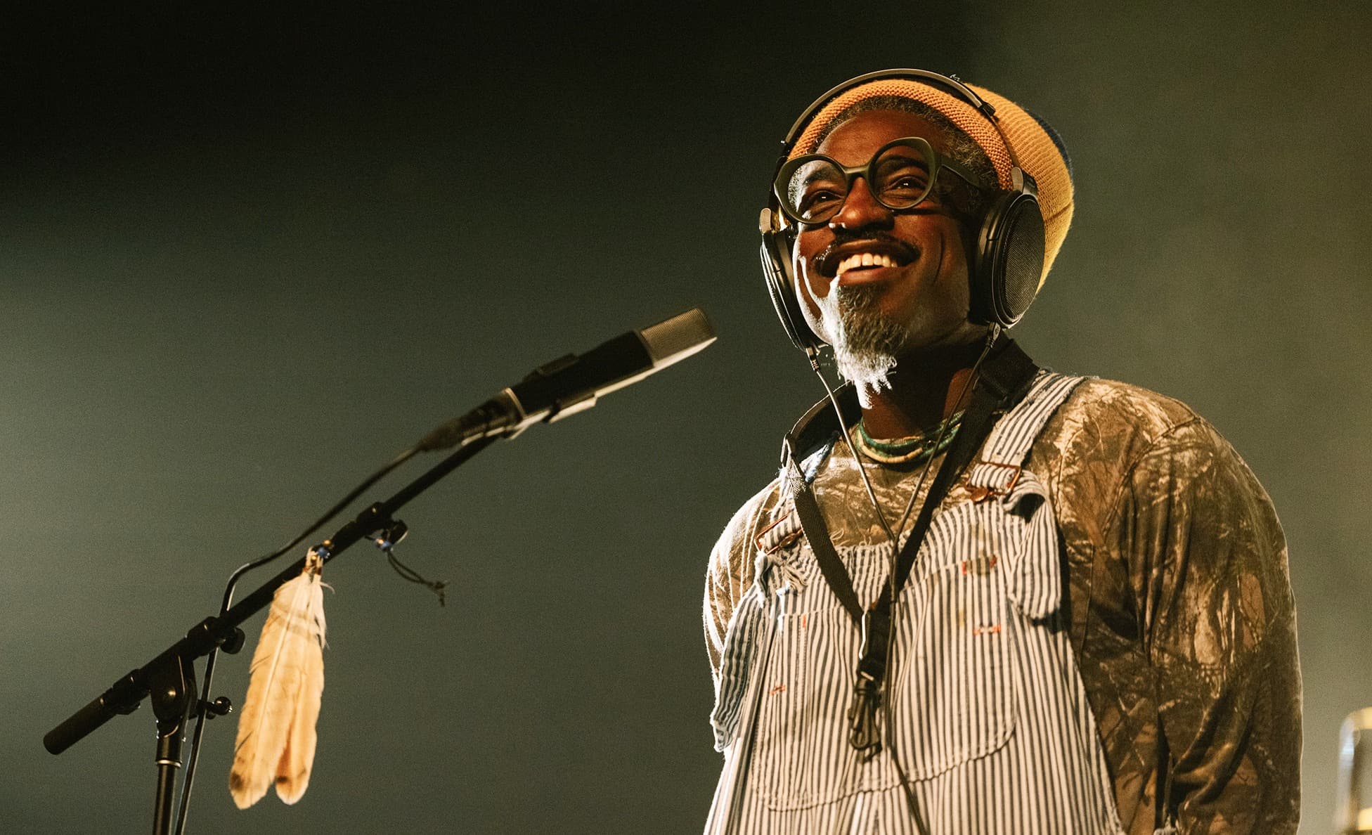 André 3000 performs at Big Ears Festival wearing headphones, round glasses and striped overalls