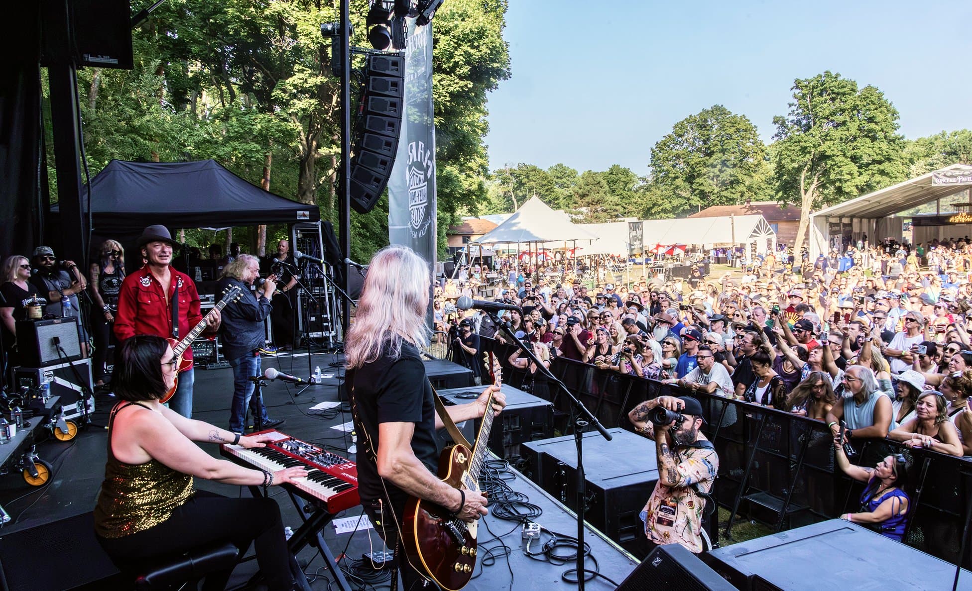View from behind a band performing at Hoochenanny Festival in a wooded amphitheater