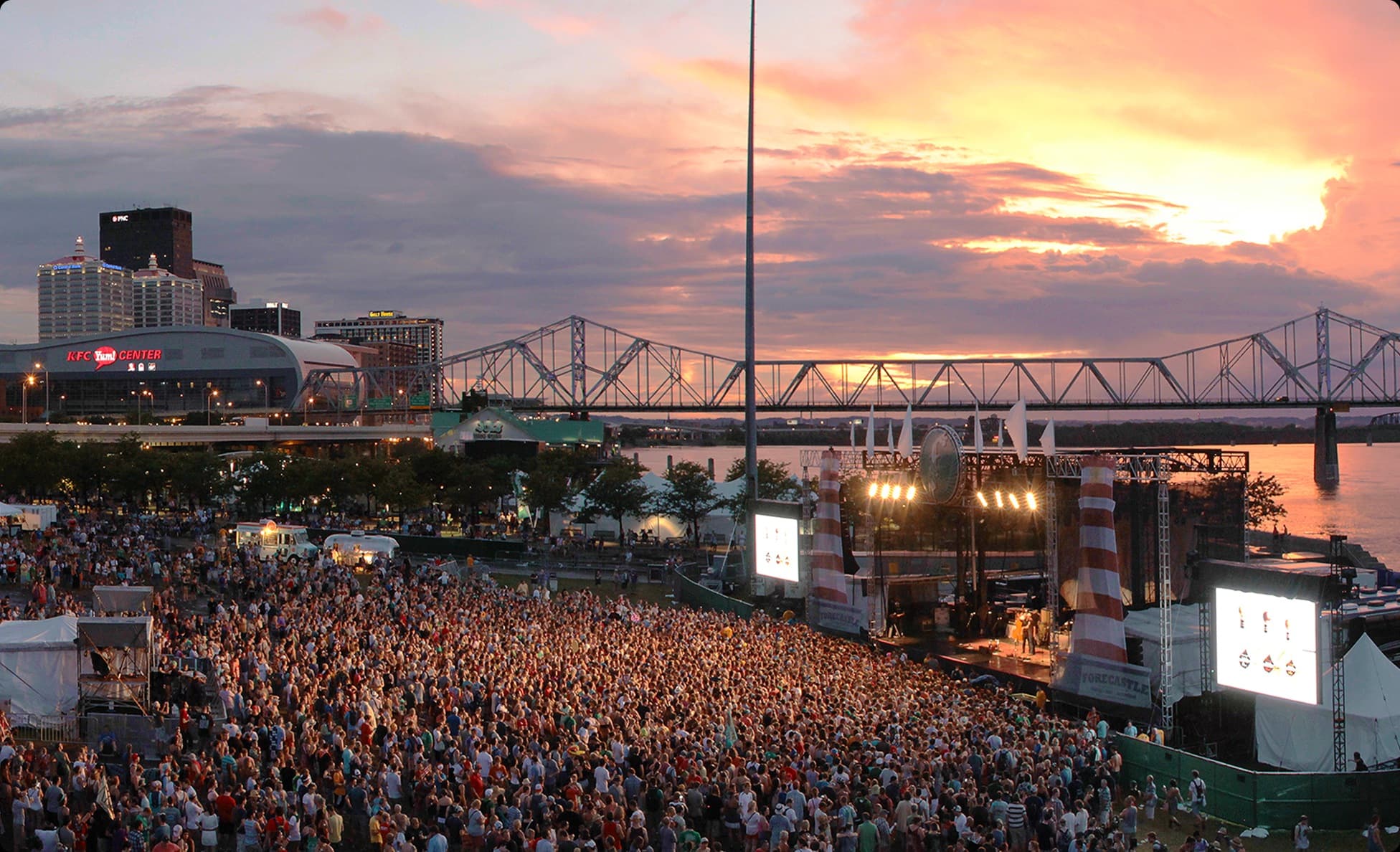 Forecastle Festival stage glowing at sunset with the Louisville skyline behind
